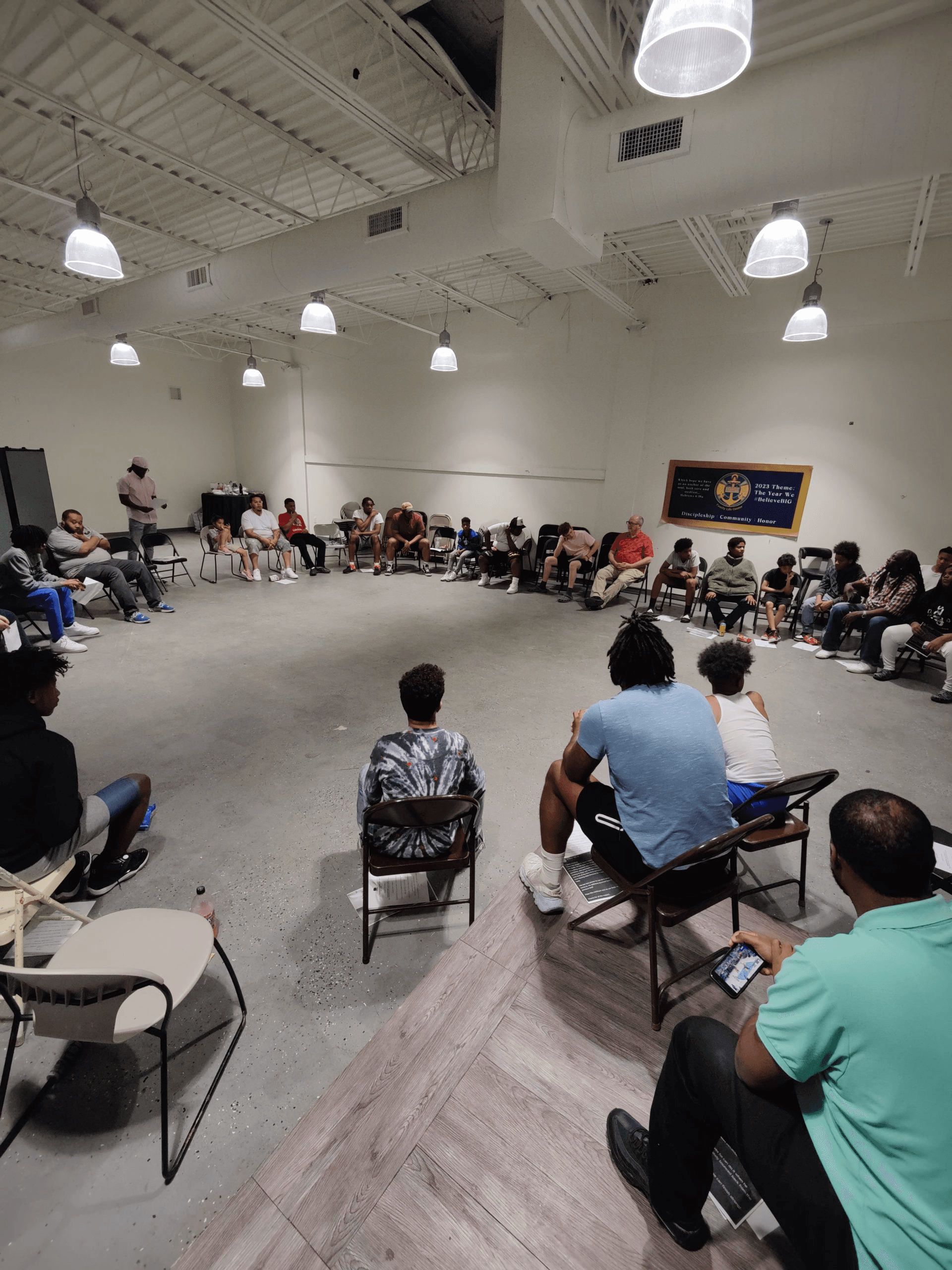 Youth and adult mentors seated in a large circle during a New B.O.Y. group discussion